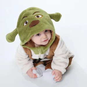 Et detaljeret Shrek-kostume til børn, der inkluderer en heldragt med grønne ternede bukser, en lys overdel med en brun vest og en grøn hue med de ikoniske Shrek-ører.