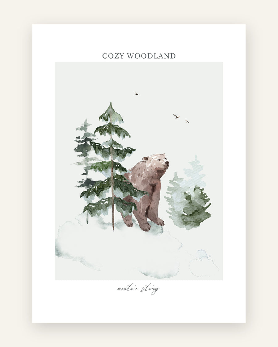 Sød børneplakat med en brun akvarelbjørn i en sneklædt grøn fyrreskov med teksten cozy woodland, til børneværelset.