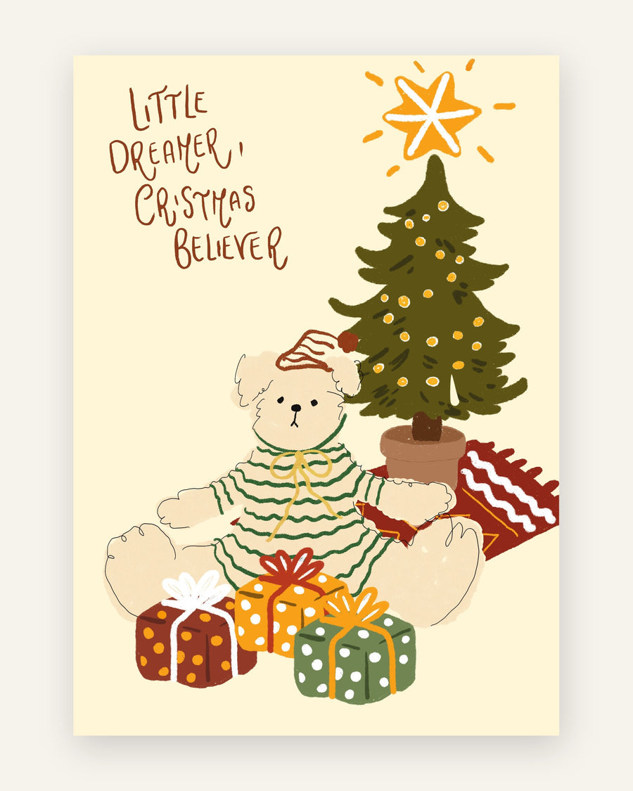 Børneplakat med sød cremehvid bjørn i stribet nattøj ved et pyntet juletræ med gaver og teksten Little dreamer Christmas believer på gul baggrund til børneværelset