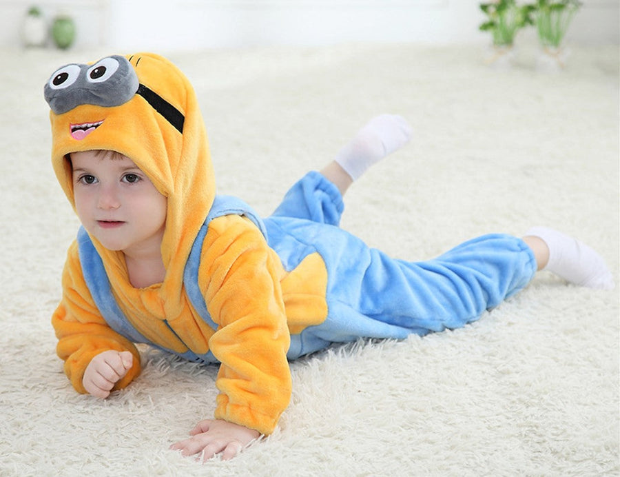 Et herligt Minion-kostume til børn, der består af en gul overdel og klassiske blå smækbukser med lomme. Dragten inkluderer en integreret gul hætte med karakteristiske briller og små hår på toppen, hvilket fuldender det sjove og genkendelige udseende fra filmene. Materialet ser blødt og behageligt ud, perfekt til leg og fastelavn.