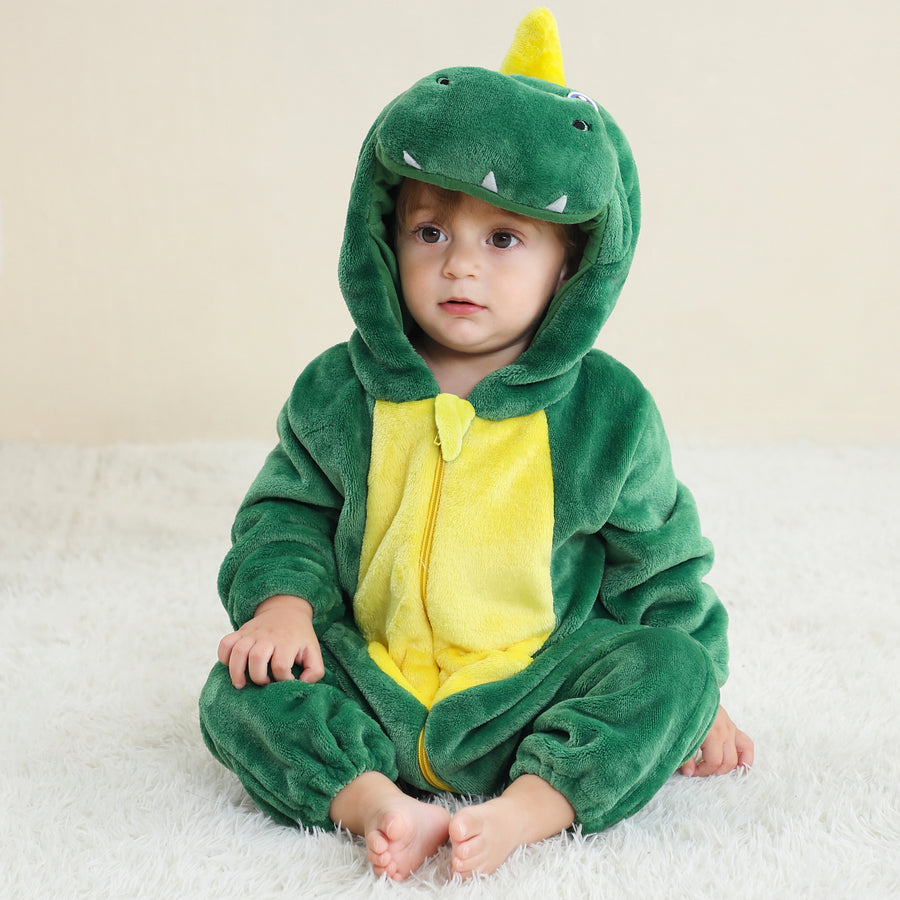 Billedet viser et sejt og detaljeret grønt T-Rex kostume til børn, set fra siden for at fremhæve den lange, polstrede hale. Dragten er lavet af blødt tekstil med et realistisk krybdyrsmønster og har en fastgjort hætte med et dinosaurhoved, der fuldfører det vilde look til leg eller fastelavn.