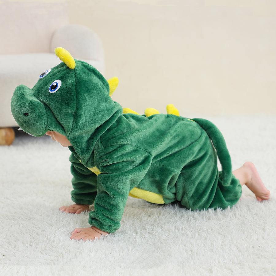 Et charmerende, grønt T-Rex kostume til børn lavet af blødt flannelmateriale. Dragten har en hvid mave, en række orange takker ned langs ryggen og en lang hale. Hætten er formet som et dinosaurhoved med store øjne og hvide tænder, hvilket gør det perfekt til både leg og fastelavn.