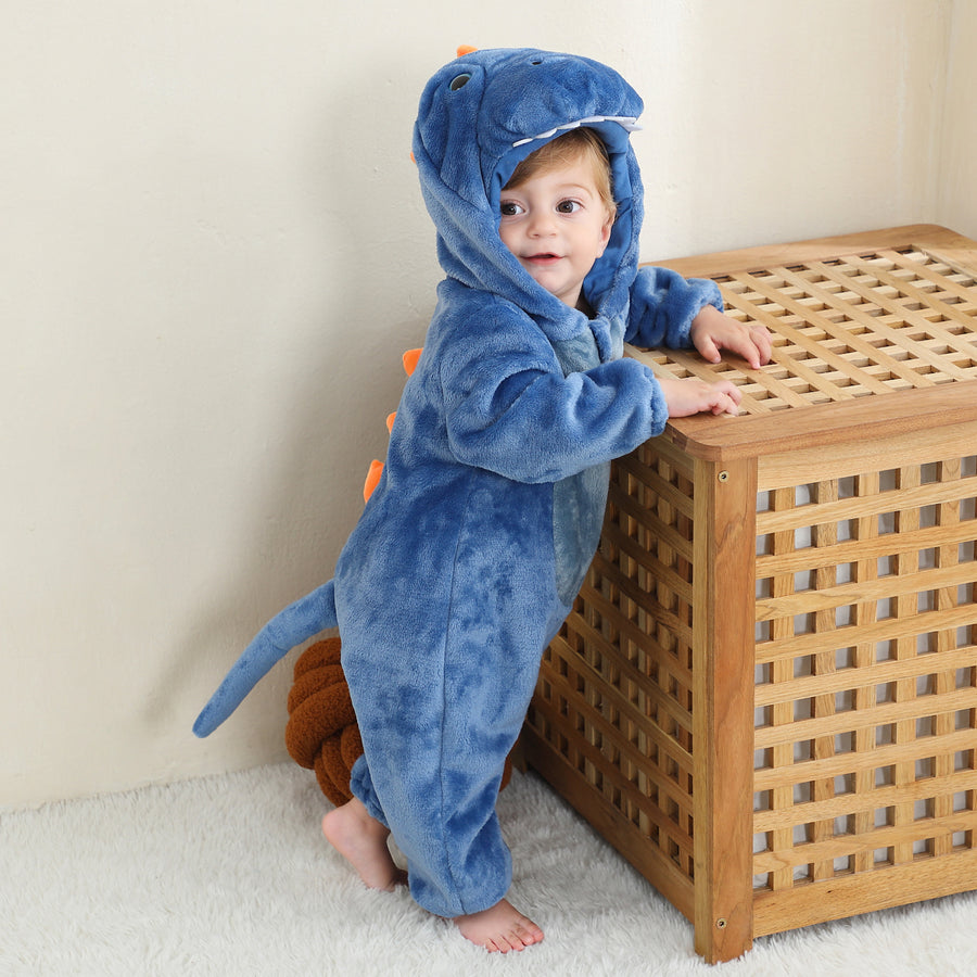 Et nuttet og blødt blåt T-Rex kostume til børn, formet som en heldragt i vamset flannel. Dragten har en hvid mave, sjove takker langs ryggen og en matchende hætte med et venligt dinosauransigt, der er perfekt til leg og udklædning.