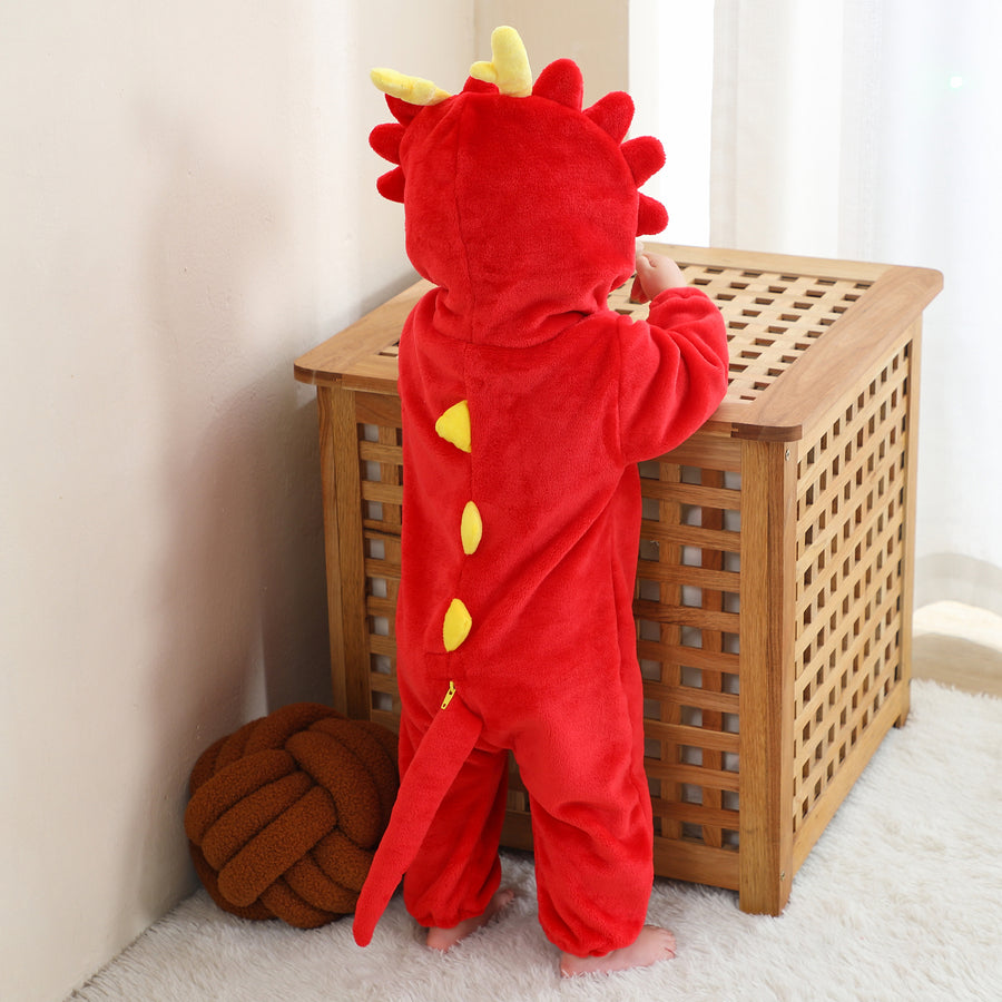 Dette billede viser et nuttet og blødt rødt dinosaurkostume til børn, set bagfra for at fremhæve de takkede pigge langs ryggen og den lille hale. Dragten er lavet af behageligt flannelmateriale og har en matchende hætte med øjne og tænder, hvilket gør den perfekt til leg eller fastelavn.