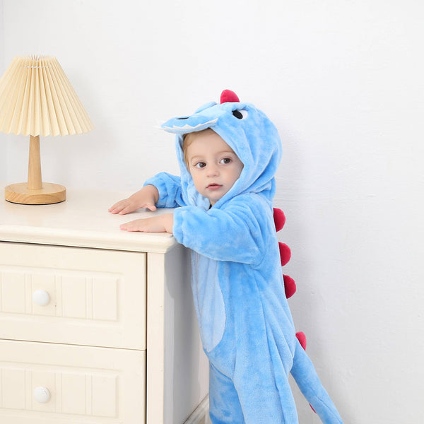Billedet viser et nuttet og blødt blåt T-Rex dinosaurkostume til børn, formet som en heldragt i behageligt flannelmateriale. Dragten har en hvid mave, en fastsyet hætte med et dinosauransigt og små hvide takker langs ryggen, hvilket gør den ideel til udklædning eller leg.