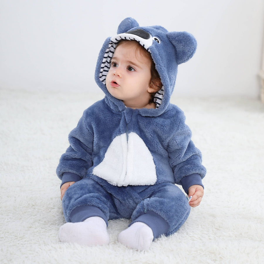 Dette billede viser et charmerende lyseblåt koala-kostume til børn, set bagfra. Dragten er lavet af blødt flannelmateriale og har en sød lille hale samt en matchende hætte med store, mørke koala-ører, hvilket gør den perfekt til både leg og fastelavn.