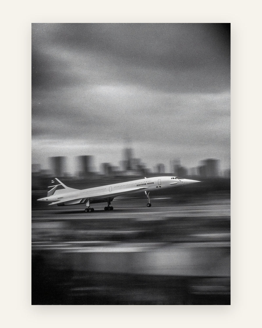 Sort-hvid plakat med et supersonisk jetfly i fart på landingsbanen foran en sløret storbyskyline, vintage fotostil
