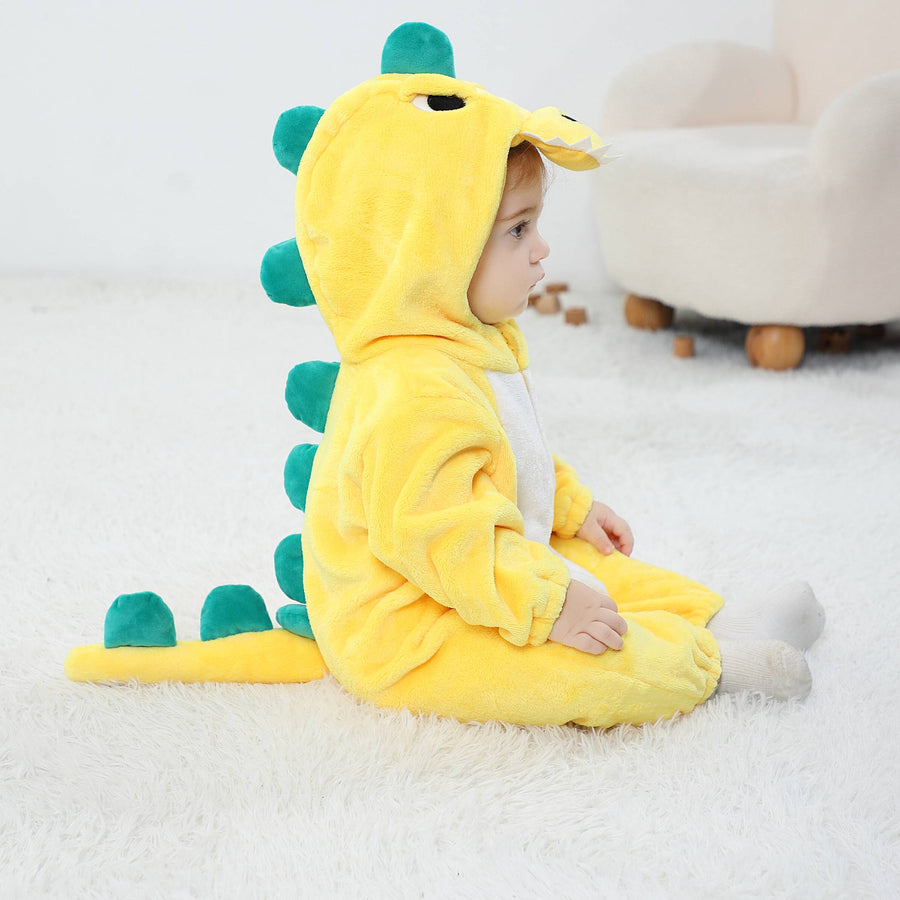Et charmerende og blødt gult T-Rex kostume til børn, formet som en heldragt i vamset flannel. Dragten har en hvid mave, en detaljeret hætte med et sødt ansigt og tænder, samt takker på ryggen og en lille hale bagpå.