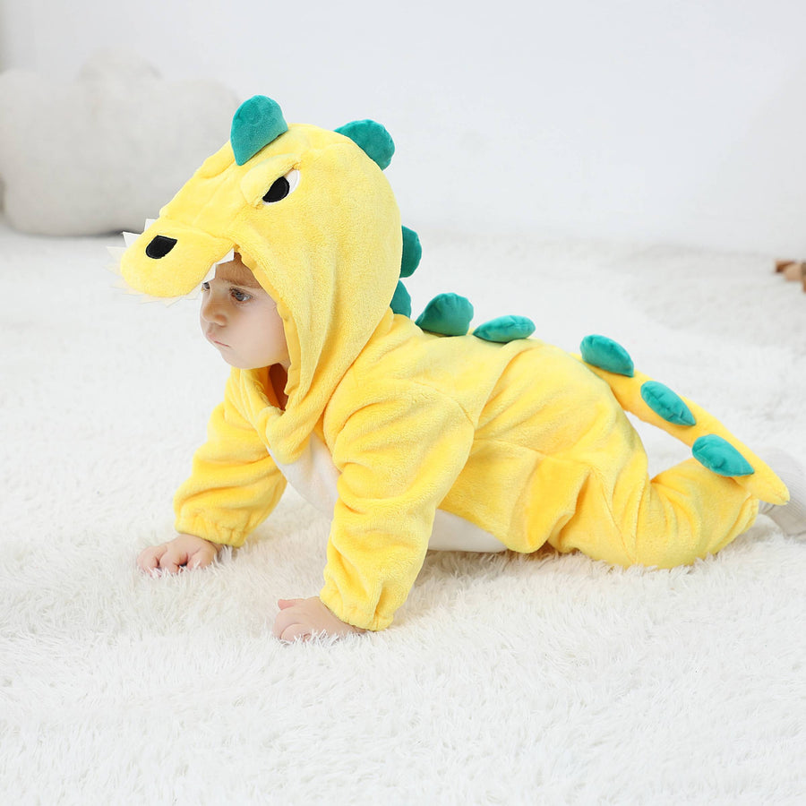 Et nuttet, gult dinosaur-kostume til børn i blødt flannelstof, set fra siden. Dragten har en hvid mave, en række grønne takker ned langs ryggen og en lang hale, hvilket skaber et sjovt og gennemført T-Rex look til leg eller fastelavn.